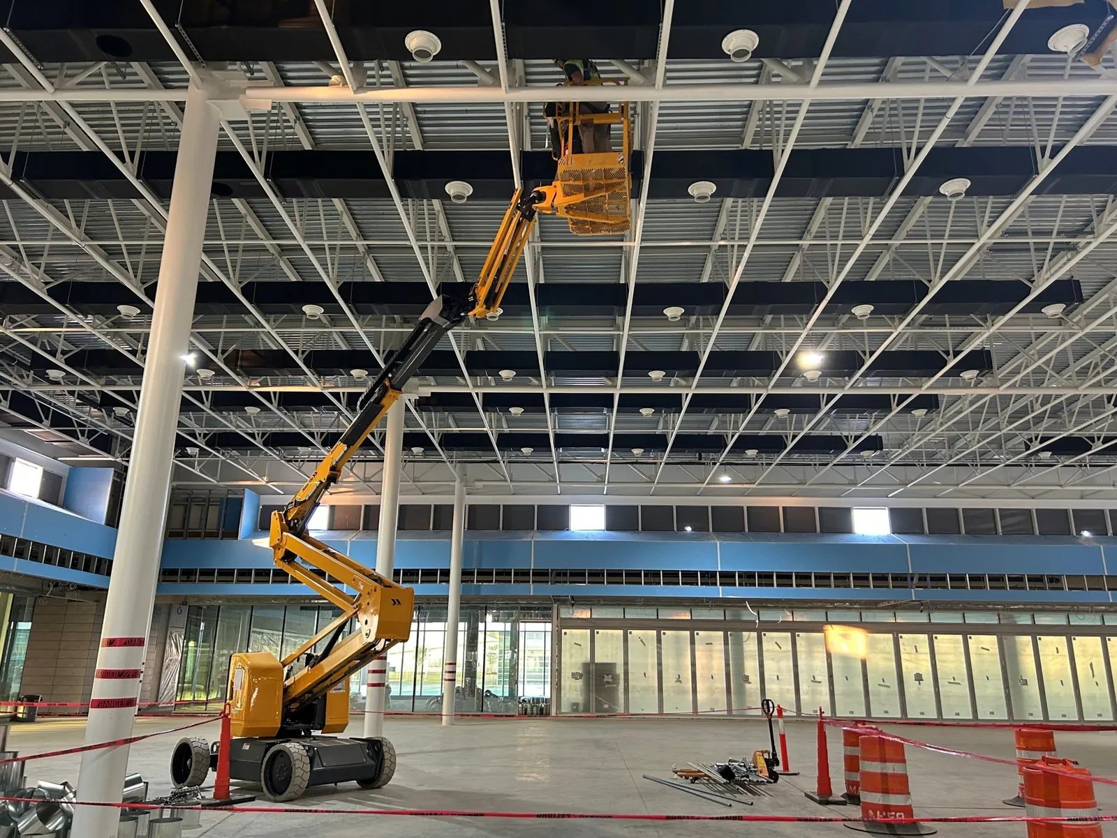 Barricaded work zone below an aerial lift inside an exhibition hall