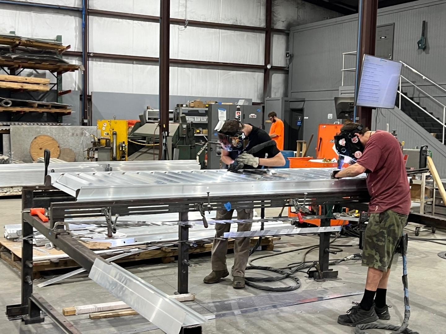 Welders joining a louver frame on the shop table