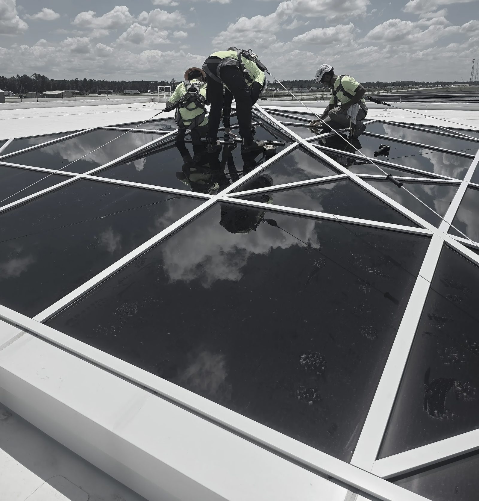 Crew tied off on a space-frame roof, setting skylight glazing