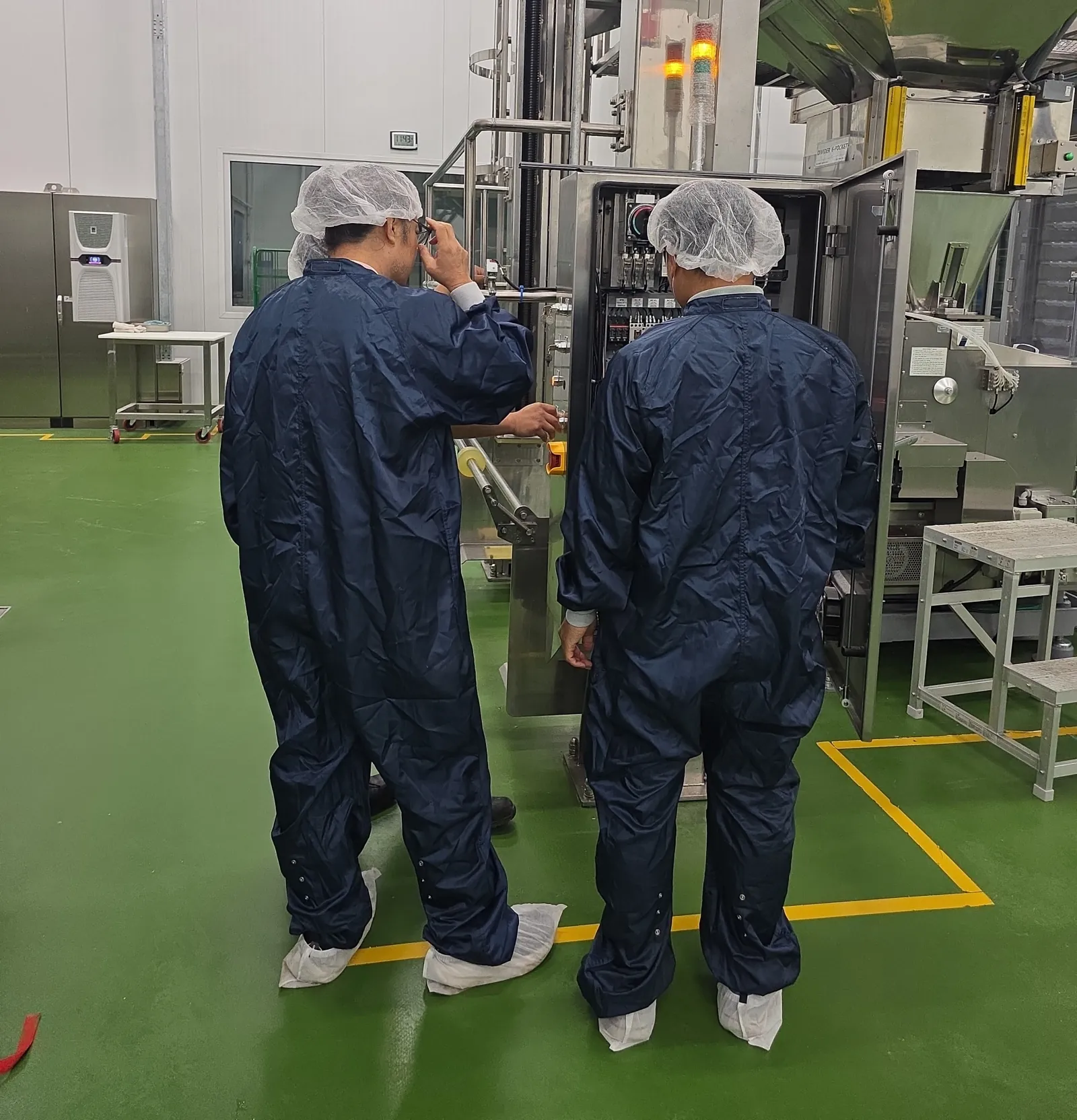 Crew in cleanroom garments at a process line